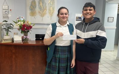 Gabriela Hernández and Axel Román from Colegio Bautista de Caguas hold a $1,500 check from Hermandad.